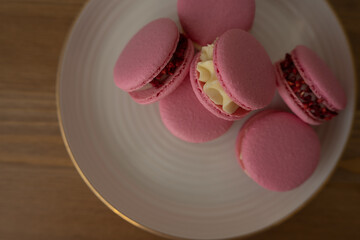 Pink sweet almond cookies with cream, a composition on a wooden table.