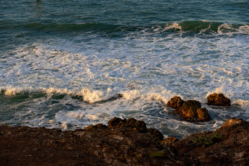 Rocky coast and waves washing over the stones near the beach. Sunset in the Dominican Republic. Caribbean background.
