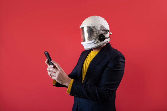 Businessman with astronaut helmet using a smart phone.