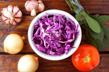 sliced raw red cabbage in ceramic bowl over rustic wooden table