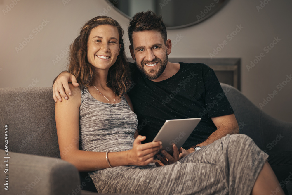Poster Taking our quality time to the sofa. Portrait of a young couple using a digital tablet together while relaxing on the sofa at home.