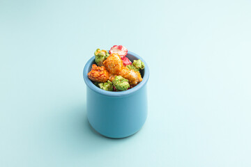 Brightly colored candied popcorn, white background, colored popcorn, colored background