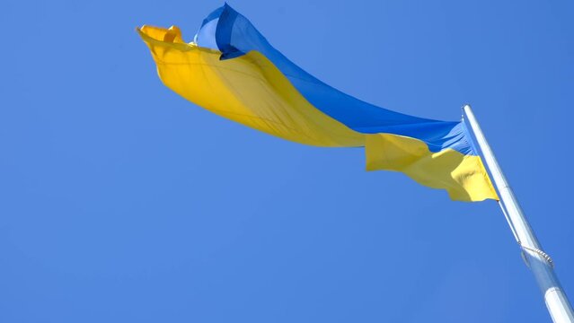 Flag of Ukraine flutters in blue sky. Large yellow blue Ukrainian national state flag. War Russia attacked Ukraine