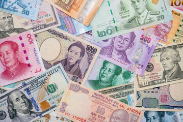 Flat lay or top view of world international banknotes vary countries background. US Dollar, Chinese yuan, Japanese yen, Euro, Indian rupee, Thai baht. Concept of Forex or global financial economic.