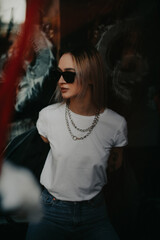 Fototapeta na wymiar Millennial blonde woman wearing black stylish leather jacket, sunglasses and silver chain. Street style portrait photography