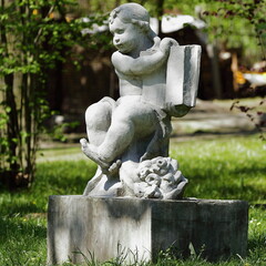 Stara rzeźba aniołka w miejskim parku botanicznym
