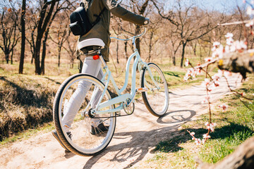 Rear view young woman walking next to her bike along footpath