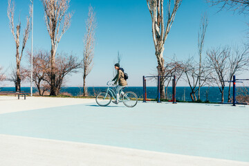 Young woman riding bicycle on sports field near the sea