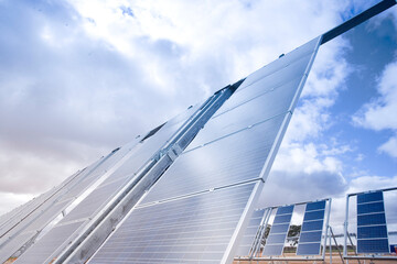 Mehrere Reihen mit Solarkollektoren zur Erzeugung von Energie, Himmel mit Sonne und Wolken 