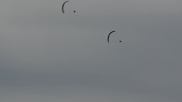 Paraglider, acropilot. Aerobatics. Acreage. A helicopter. Blue wing. Gray sky.