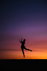 Girl Silhouette happy jumping on colorful sunset sky