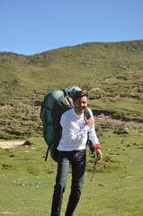 Obraz premium A cheerful young male tourist walking with carrying Parachute backpack in the mountain 