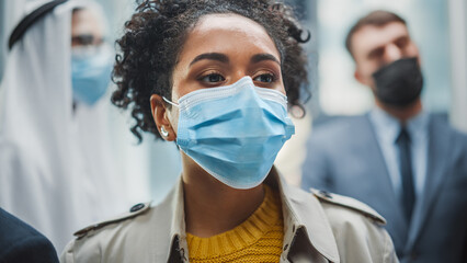 Four Diverse Multiethnic International People Wearing Protective Face Masks Ride a Glass Elevator...