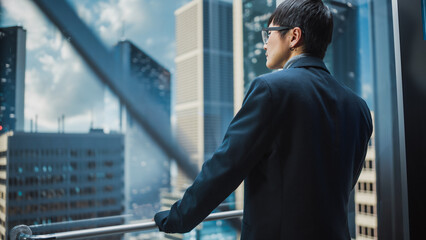 Stylish Japanese Businessman Riding Glass Elevator to Office in Modern Business Center. Male...