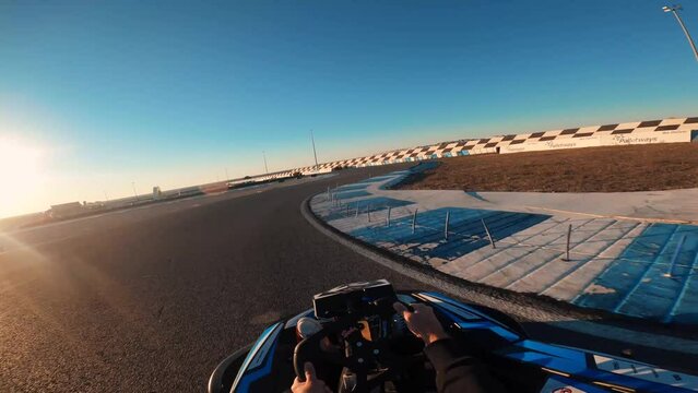 Point Of View Man Driving A Kart Outdoor At Sunset. Racers Driving Karts On A Race Track. First Person View Of Steering A Go Cart While Racing In A Fun Competition