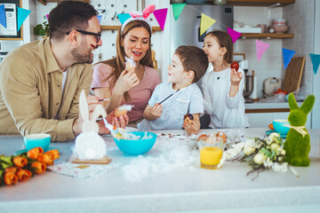 Family painting Easter eggs together at table. Laughing family on Easter. Happy young family with two children painting Easter eggs at home. Easter. Happy family
