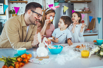 Happy young family decorating Easter eggs. Happy family spending time together during Easter holiday at home.  Two cute kids painting easter eggs with mom and dad.