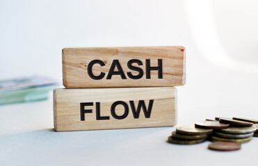 The inscription CASH FLOW on wooden cubes isolated on a light background. Concept word forming on wooden cube. Business, economics and finance concept.
