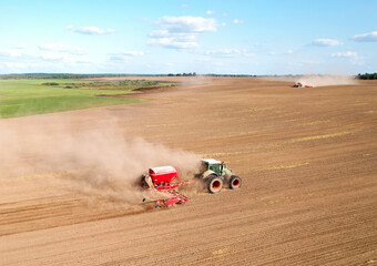 Tractor plowing farm field, sowing seed on plowed field. Spring planting season. Tractor with disk harrow on plowing field. Farming seeding. Seed sowing and land cultivating. Tractor Plowing field..