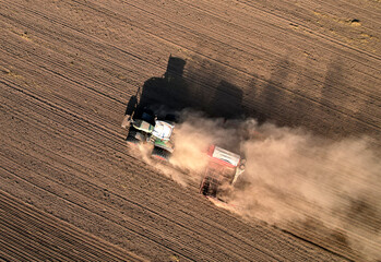 Tractor plowing farm field, sowing seed on plowed field. Spring planting season. Tractor with disk...