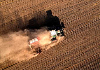 Tractor plowing farm field, sowing seed on plowed field. Spring planting season. Tractor with disk...