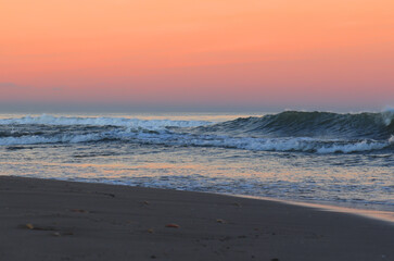 Coast with waves in sea on sunset. Waves in sea during storm and wind. Wave from the sea goes on land to the beach. Splashing Waves in ocean. Wave at Rising Storm near Seashore or Coastline. Seaside.