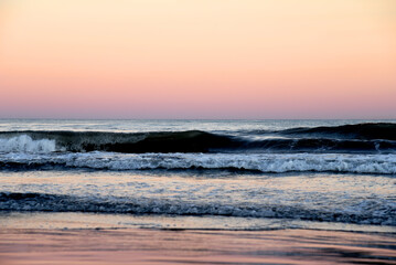 Coast with waves in sea on sunset. Waves in sea during storm and wind. Wave from the sea goes on land to the beach. Splashing Waves in ocean. Wave at Rising Storm near Seashore or Coastline. Seaside.