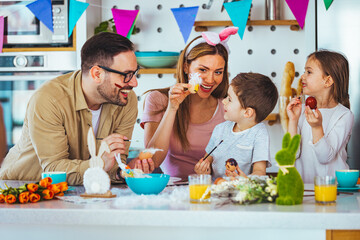 Family painting Easter eggs together at table. Laughing family on Easter. Happy young family with...