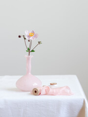 Fototapeta na wymiar A single pink flower in a pink vase on a white table. Minimal styling