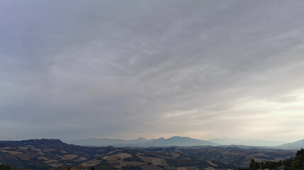 Mare di nuvole grigie e luminose nel cielo sopre le montagne le valli e le colline