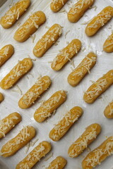 Raw Kaasstengels (Dutch cheese finger cookies) dough on aluminum tray are ready to bake