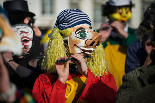 Basel - Switzerland - 9 March 2022 - portrait of masked people wearing traditional costume playing flute parading in the street