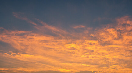 Sunset sky clouds in the evening with orange sunlight and dark blue sky background