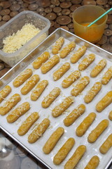Raw Kaasstengels (Dutch cheese finger cookies) dough on aluminum tray are ready to bake
