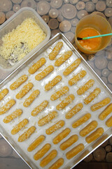 Raw Kaasstengels (Dutch cheese finger cookies) dough on aluminum tray are ready to bake