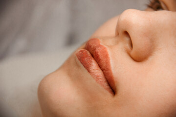 Fototapeta premium intermediate result beauty procedure. closeup permanent lip tattoo. side view. beauty concept, free space