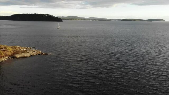 Aerial of a sailboat sailing through the San Juan Island channel in 4k