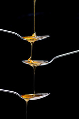 fresh honey pouring over three spoons