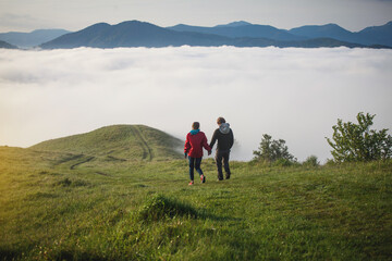 Obraz premium Young Couple Walks Holding Hands in Amazing Carpathian Misty Mountain Scenery