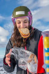 Woman with brown hair, wearing ski wear, taking a break from skiing in Stryn, Norway, Holding a bag...