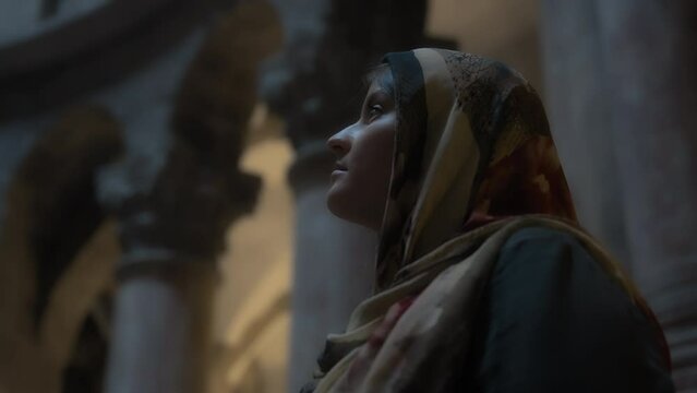 Woman in traditional clothes standing inside the church. Slow motion, dolly shot. 