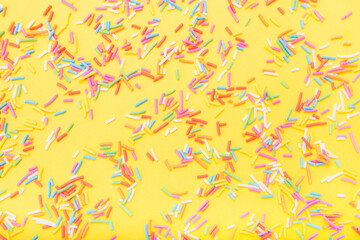 Colorful festive sugar sprinkles  on yellow background. Flat lay style. Top view. Place for design. Easter background.