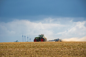 Ackerbau in der Picardie, Frankreich. Traktor auf dem Feld mit Windrädern im Hintergrund und...