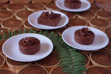 chocolate dessert with filling of caramel, nuts and nougats. The cake is covered with chocolate on a wooded background with a morning natural light