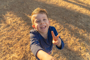 Niño contento feliz tomándose fotografía selfie jugando posando y disfrutando en el parque un...