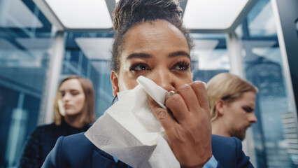 Close Up Portrait of a Middle Aged Woman Sneezes in a Crowded Glass Elevator in a Modern Office Building. Businesswoman Covers Her Face, but Other People Are Afraid to Catch the Virus in a Lift.