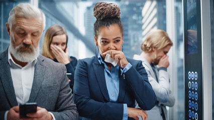 Middle Aged Woman Sneezes in a Crowded Glass Elevator in a Modern Office Building. Businesswoman Covers Her Face, but Other People Are Afraid to Catch the Virus and Microbes in a Lift.