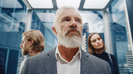 Portrait of a Confident Middle Aged Successful Businessman Riding in Crowded Glass Elevator in a Modern Business Center. Senior Manager on the Way to Office in a Lift.
