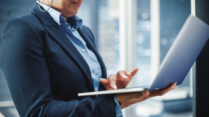 Close Up Portrait of a Black Female Riding Glass Elevator to Office in Modern Business Center. African American Manager Using Laptop Computer to Check Schedule, Social Media and Work Emails in a Lift.