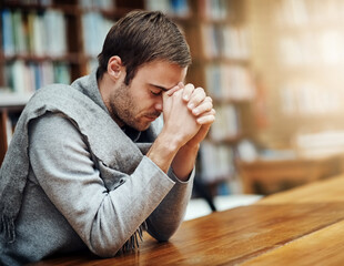 Seeking help from above. Cropped shot of a handsome young man praying for help with his upcoming university exams.